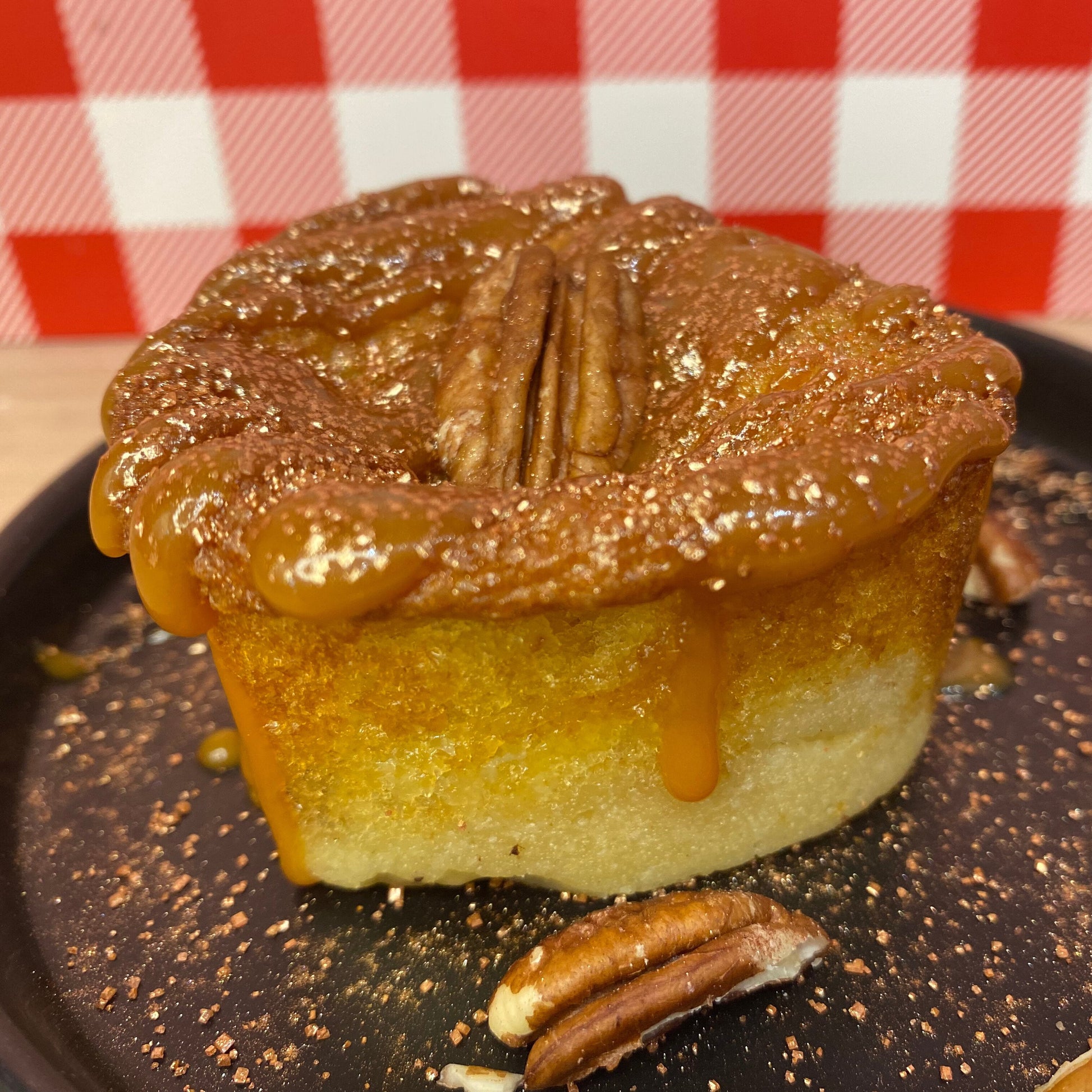 Photo d'un Muffkie, une fusion entre un muffin et un cookie. Le Muffkie est montré de face, avec des noix de pécan visibles sur le dessus. Sa texture semble légère et moelleuse, avec un nappage au caramel beurre salé.